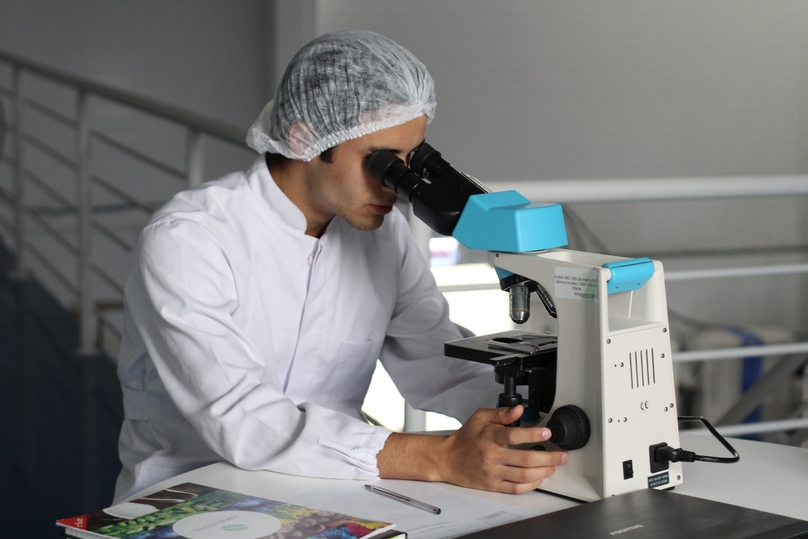 lab technician looks through microscope